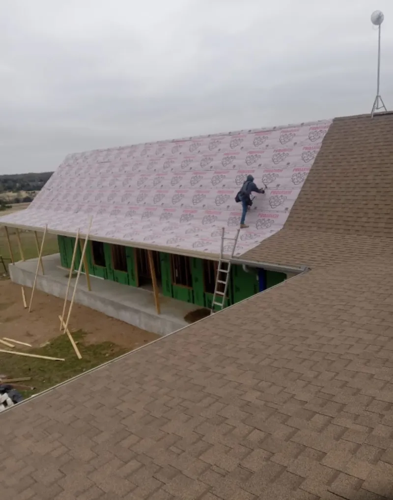 Worker preparing underlayment for a metal roof installation in Ives Estates